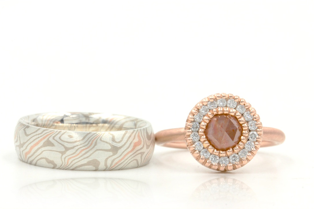 Rose gold diamond engagement ring beside a patterned mokume-gane wedding band in 13 layer palladium white gold, sterling silver and 14k rose gold. 